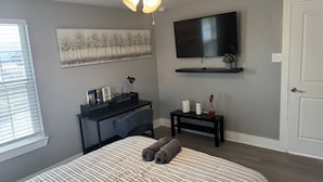 A bedroom with a bed, a desk, a chair, a TV, and a ceiling fan. - Amazing 2-bedroom house in beautiful Houston with AC (Houston)