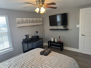 A bedroom with a bed, a desk, a chair, a TV, and a ceiling fan. - Amazing 2-bedroom house in beautiful Houston with AC (Houston)
