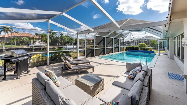 Un espace extérieur abrité comprenant une piscine, des chaises longues et un barbecue.