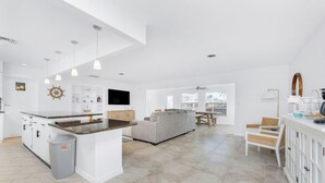 Une cuisine spacieuse dotée d’un îlot central, un coin repas avec une table et des chaises, et un salon avec un canapé.