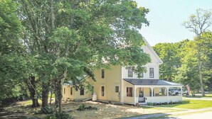 A two-story house with a porch, surrounded by trees. - Amazing 2-bdrm apartment in quintessential coastal Friendship, Maine - 1st floor (Friendship)