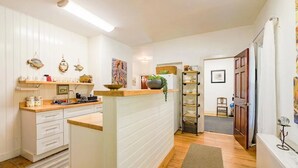 A kitchen with white cabinetry, a central island, and a wooden countertop. There are decorative items on the shelves and a plant on the island. - Amazing 2-bdrm apartment in quintessential coastal Friendship, Maine - 1st floor (Friendship)