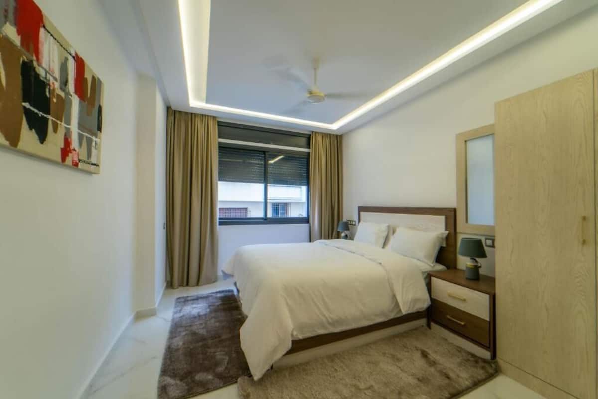 Un dormitorio moderno con una cama, una mesita de noche y un ventilador de techo.