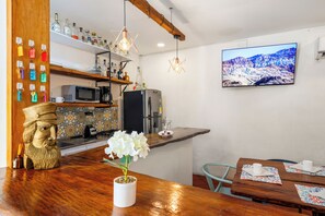A kitchen with a wooden bar, a white vase with flowers, a mounted TV, and a decorative bust. - Casa Trinidad - Luxury 9BR House in the Old City w/ Cook & Security (Cartagena de Indias)
