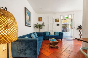 A spacious living area with a blue sofa set, a wooden coffee table, and a large woven lamp. - Casa Trinidad - Luxury 9BR House in the Old City w/ Cook & Security (Cartagena de Indias)