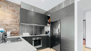 A modern kitchen with grey cabinets, a stainless steel range hood, and a built-in oven. - Waterfront Marina Escape (Patterson Lakes)