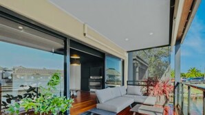 A modern living room with a large glass wall, a sofa, and a coffee table. - Waterfront Marina Escape (Patterson Lakes)