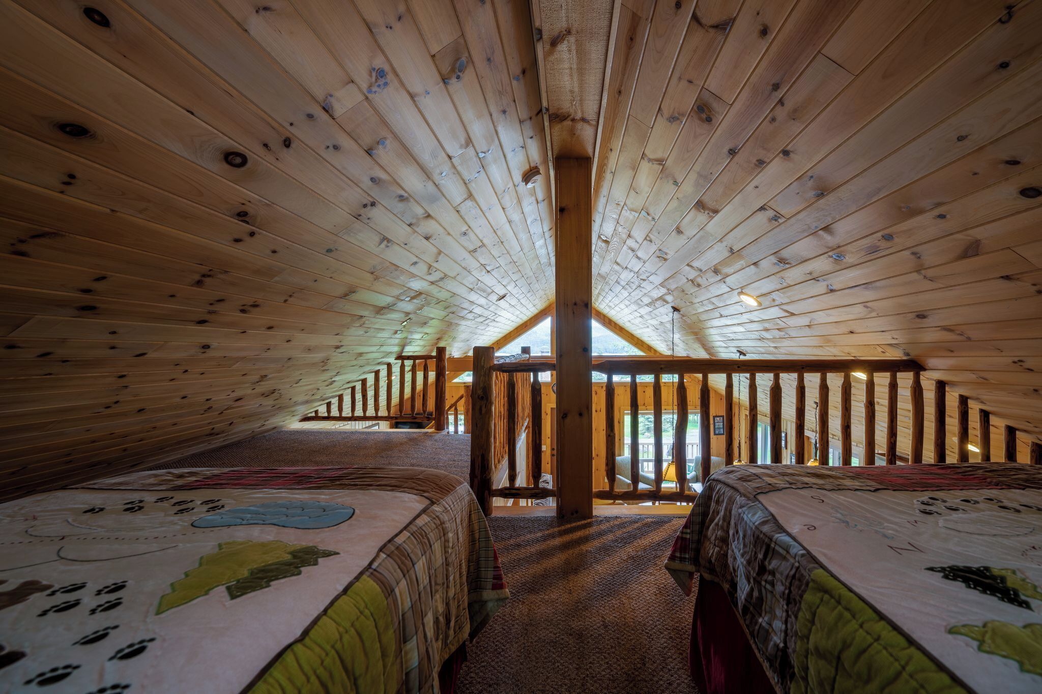 Una habitación con techos altos, vigas de madera, dos camas con colchas y vistas por una ventana.