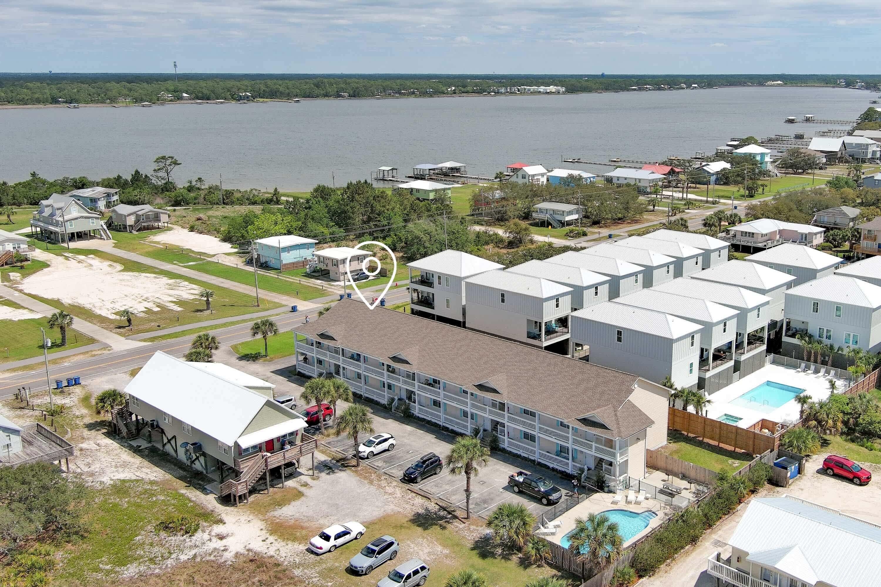 A coastal residential area with multiple houses, a large building with a swimming pool, and a view of the sea.