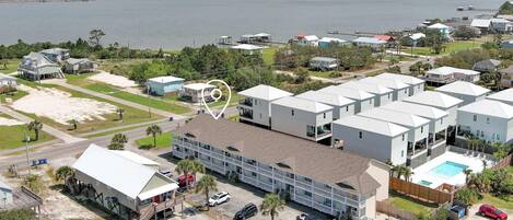 A coastal residential area with multiple houses, a large building with a swimming pool, and a view of the sea.
