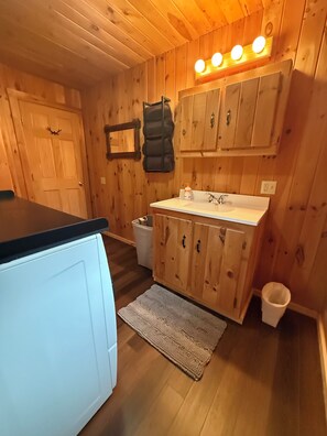 Un intérieur en bois comprenant un coin cuisine, un évier, des placards, un miroir et un luminaire fixé au plafond.