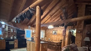 A rustic wooden interior with a kitchen, dining area, and living room. - Cozy 3-bedroom rustic lodge in Island Falls perfect for your getaway (Island Falls)