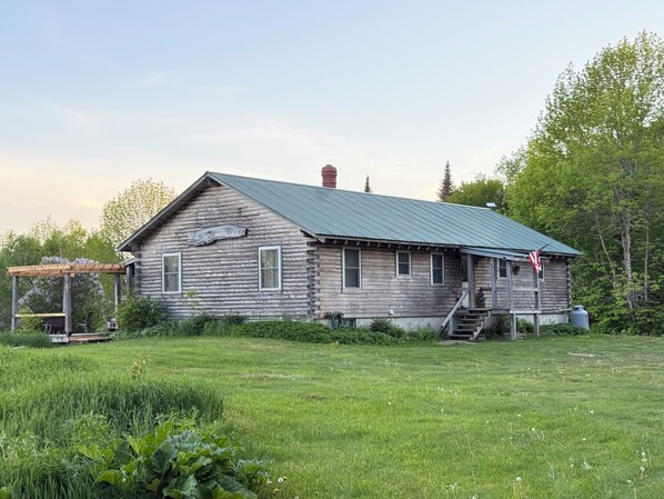 Une cabane en bois rustique, dotée d’un toit en métal, d’un porche et d’une enseigne indiquant qu’un service de guide est proposé.