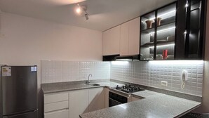Eine moderne Küche mit weißen Schränken, einem Edelstahlkühlschrank, einer Granitarbeitsplatte und einem eingebauten Herd.