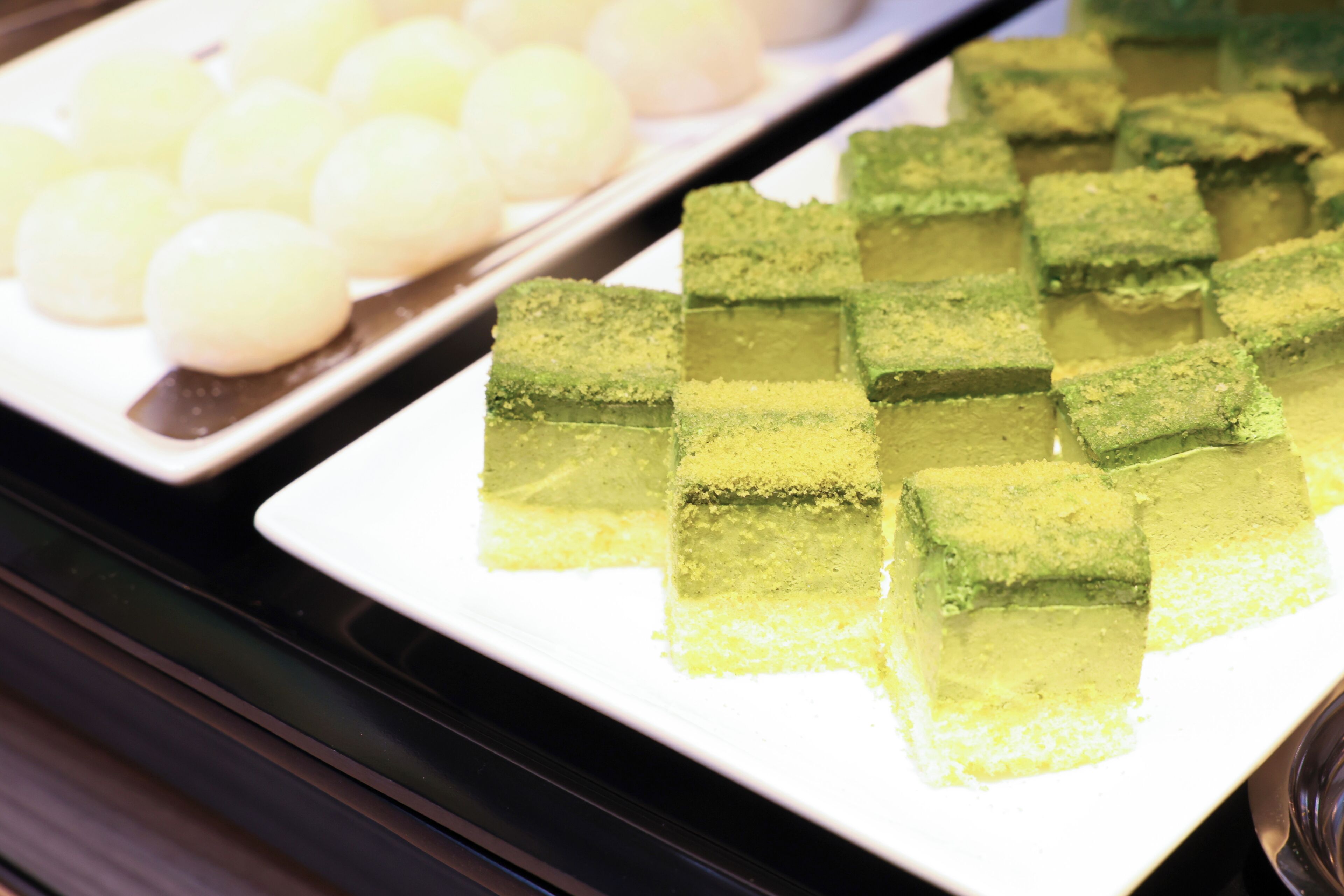Exposição de alimentos, incluindo sobremesas verdes e brancas.