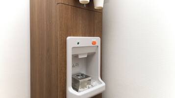 A wall-mounted urinal with a push button, a warning label, and a metal object inside.