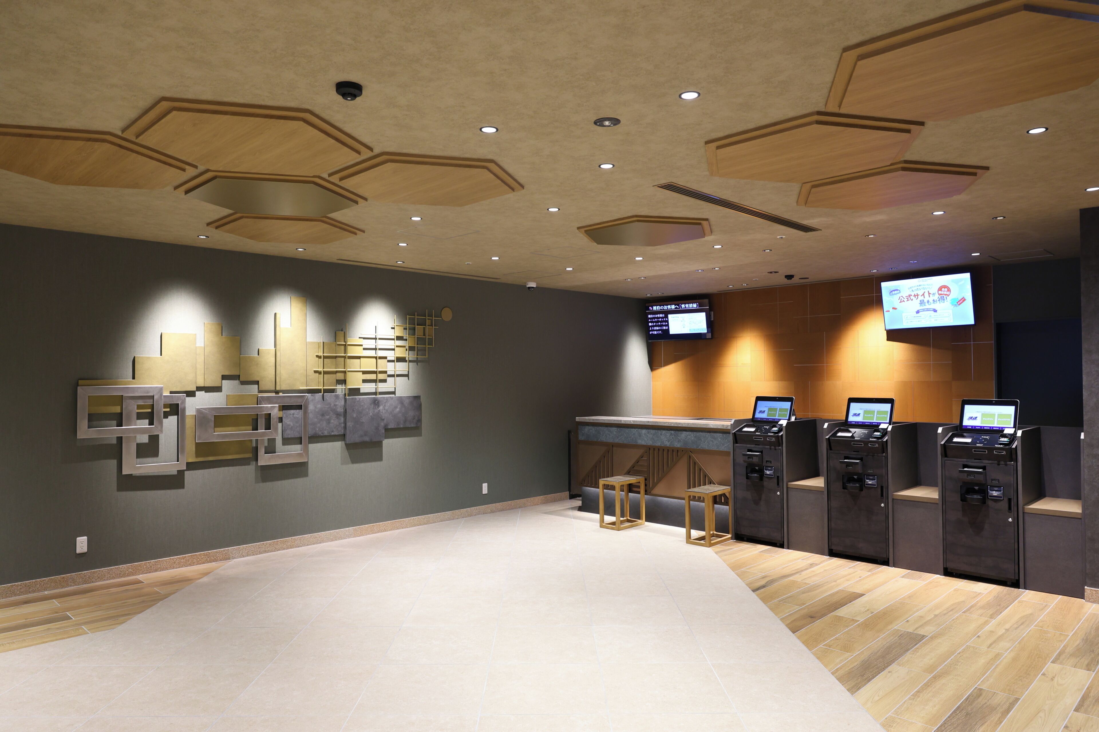 A lobby with a modern design, including a reception desk, seating area, and a digital display.