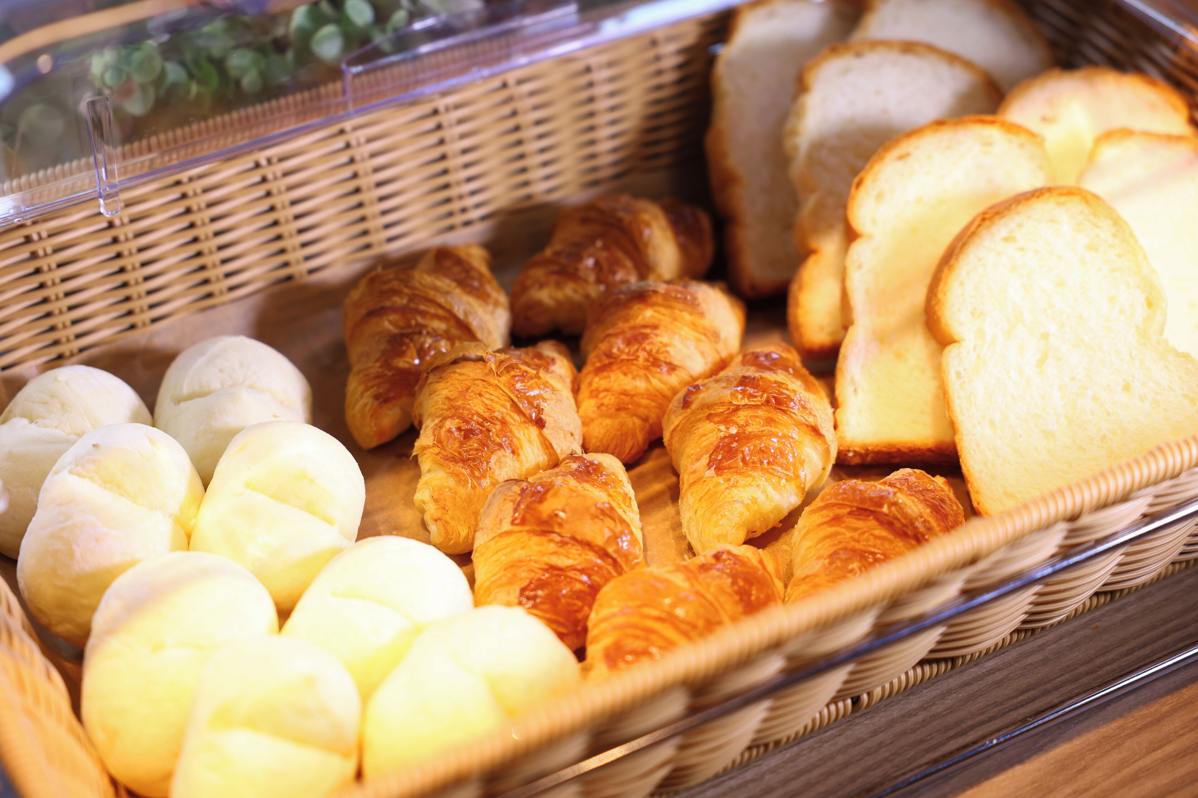 Una cesta con una variedad de productos horneados, incluyendo pan y pasteles.