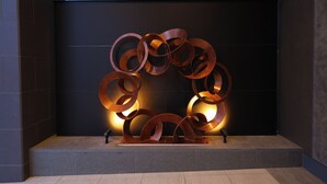 A metallic sculpture with interlocking rings, placed on a platform against a dark wall. - Natural Hot Springs Higoromo no Yu Dormy Inn Yokkaichi (Yokkaichi)
