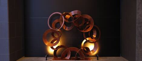 A metallic sculpture with interlocking rings, placed on a platform against a dark wall.