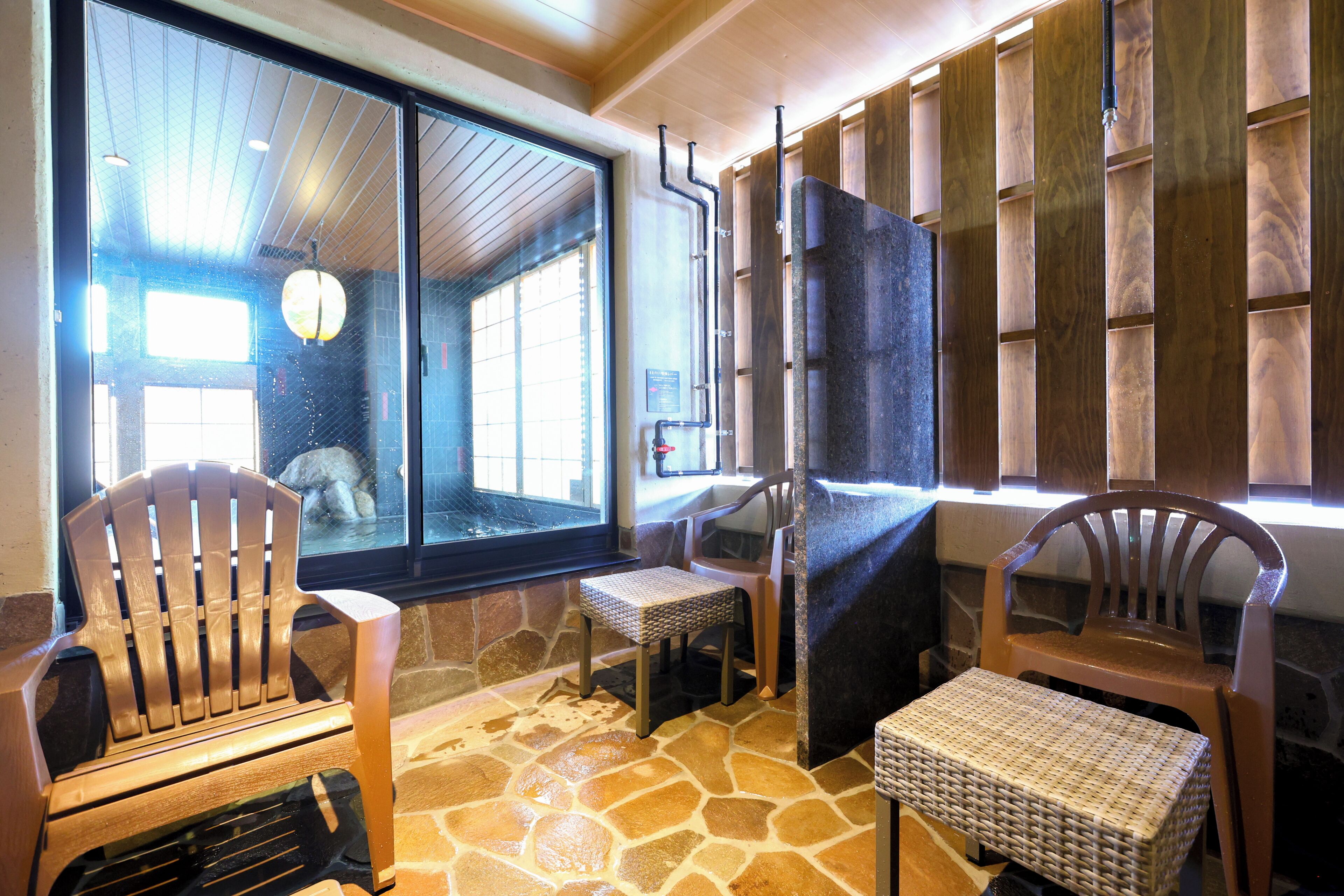 A room with a stone floor, wooden chairs, a small table, and a window with a view.