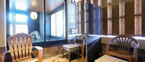 A room with a stone floor, wooden chairs, a small table, and a window with a view.