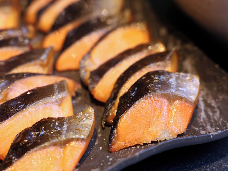 A tray of sliced salmon with a dark glaze.