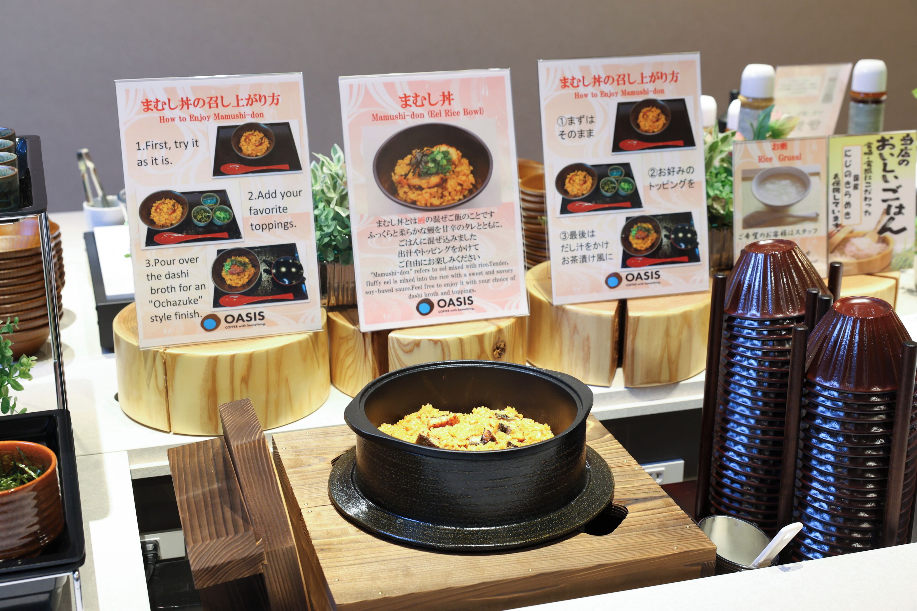 Un escaparate de comida con letreros en japonés, un tazón negro de comida y taburetes de madera.