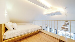 Un dormitorio moderno con una cama plataforma de madera, ropa de cama blanca, un tragaluz y vistas al exterior.