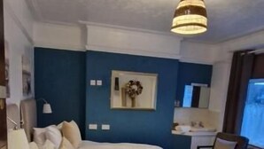 A bedroom with a large bed, a desk, and a chair. There is a dresser and a lamp on the desk. - Black Sheep Lodge (Holyhead)