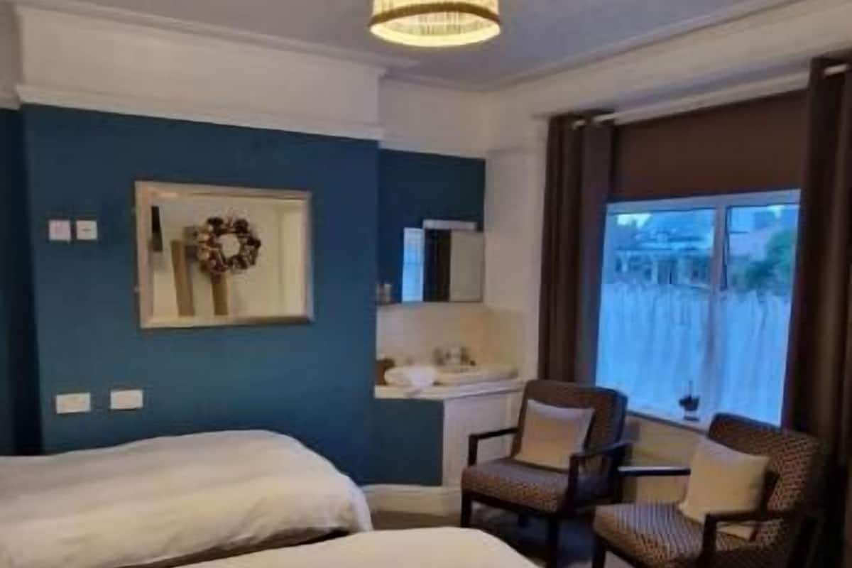 A hotel room with two beds, a desk, and two chairs.