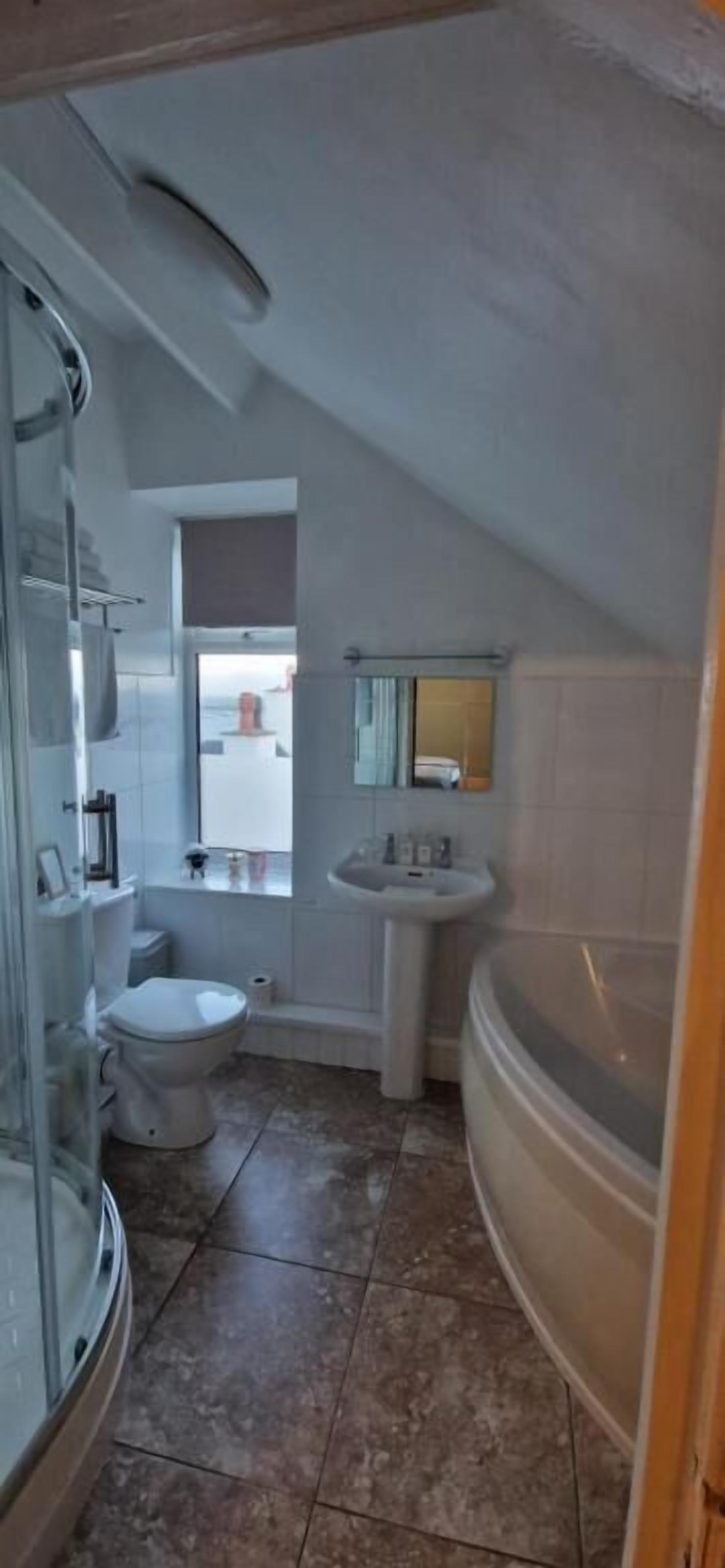 A bathroom with a shower, toilet, sink, and bathtub.