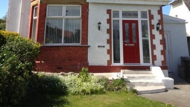 A two-story house with a red front door, white trim, and a small porch. - Black Sheep Lodge (Holyhead)