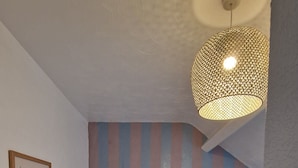 A bedroom with a bed, a nightstand, a wall-mounted lamp, a 'Meet Me At The Beach' sign, and a striped wall. - Black Sheep Lodge (Holyhead)