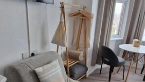 A room with a grey sofa, a hanging chair, a small table, and a TV mounted on the wall. - Black Sheep Lodge (Holyhead)