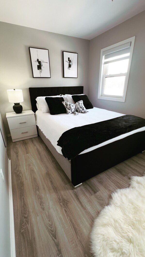 Une chambre à coucher avec un lit, une table de chevet, une lampe et une fenêtre.
