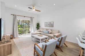 A modern living room with a sofa, armchairs, a coffee table, and a TV. - Poolside Near Disney 1st Floor *no resort fees* (Davenport)
