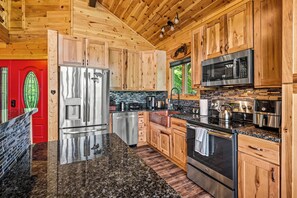 Eine moderne Küche mit Holzschränken, Edelstahlgeräten, Granitarbeitsplatten und einer roten Tür.