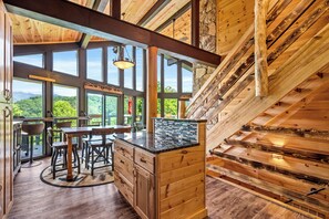 Eine geräumige Küche mit großen Fenstern, Holzschränken und einer zentralen Kochinsel.
