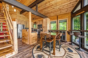Ein Holzblockhaus-Interieur mit Küche, Essbereich und großen Fenstern.