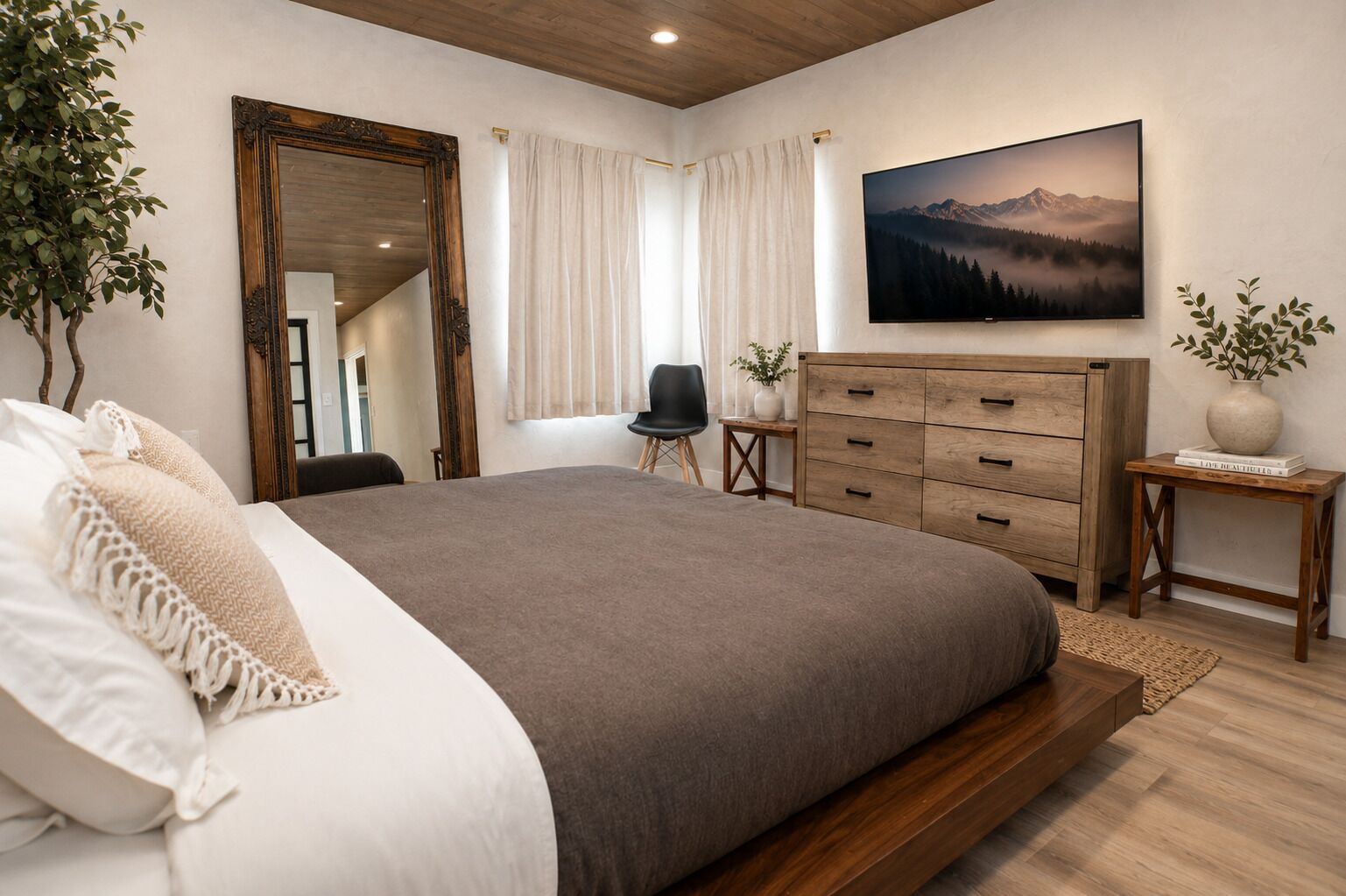 A bedroom with a large bed, wooden dresser, and a painting of a mountain landscape.