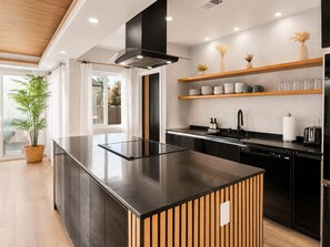 A modern kitchen with a central island, black cabinetry, wooden accents, and built-in shelves. - Burbank Getaway (Burbank)