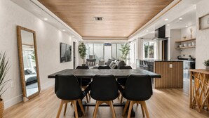 A modern dining area with a wooden table, black chairs, and a large mirror.
