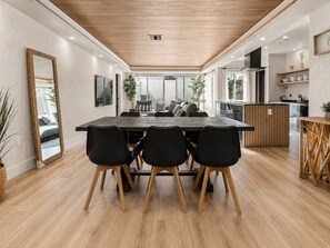 A modern dining area with a wooden table, black chairs, and a large mirror. - Burbank Getaway (Burbank)