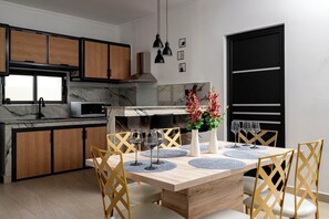 Eine moderne Küche mit Holzausstattung, einer eingebauten Mikrowelle und einem Essbereich mit Holztisch und Stühlen.