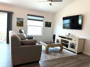 Ett vardagsrum med en soffa, ett soffbord, en tv och konstverk på väggarna.