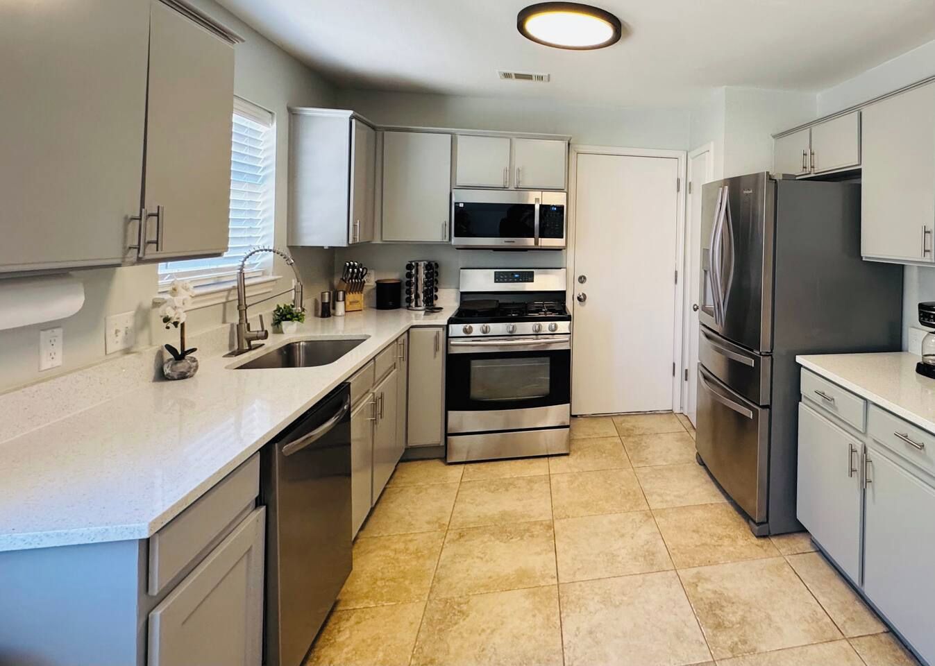 A compact kitchen with a stove, microwave, refrigerator, and sink.