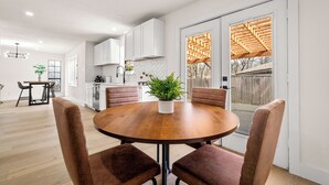 A modern kitchen with white cabinets, a wooden dining table with four chairs, and a potted plant on the table. - Fully Renovated Furnished Home in Hurst – Perfect for Mid-Term Stays (Hurst)