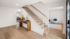 A spacious room with a wooden floor, a staircase with white balusters, and a dining area with a wooden table and chairs. - Fully Renovated Furnished Home in Hurst – Perfect for Mid-Term Stays (Hurst)