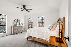 A bedroom with a bed, a dresser, a ceiling fan, and large windows. - Fully Renovated Furnished Home in Hurst – Perfect for Mid-Term Stays (Hurst)